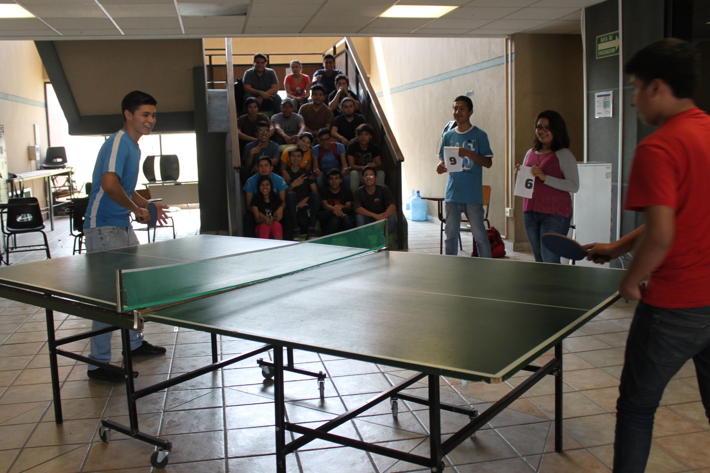 La imagen muestra a estudiantes de la universidad jugando pin pon.